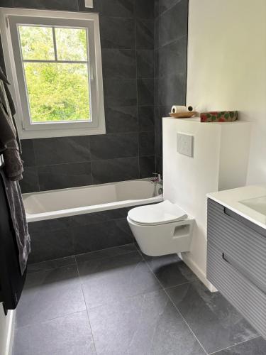 La salle de bains est pourvue de toilettes, d'une baignoire et d'une fenêtre. dans l'établissement La vacancière, à Cucq