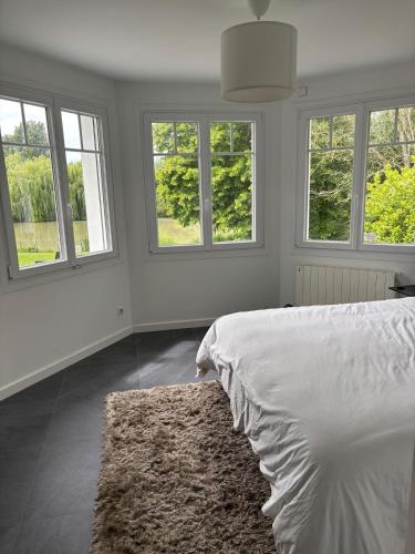 une chambre blanche avec des fenêtres et un lit avec un tapis dans l'établissement La vacancière, à Cucq