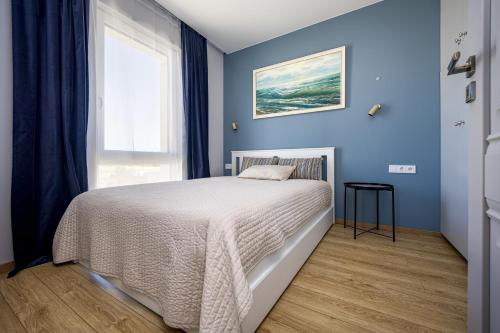 パランガにあるKauko Apartment, TAKAS Į JŪRĄ, Šildomas baseinasの青いベッドルーム(ベッド1台、窓付)