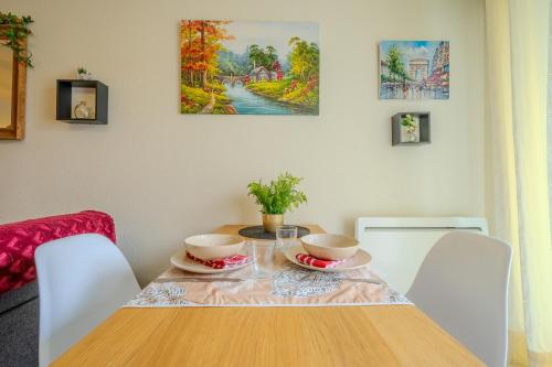 a dining room table with two bowls on it at Appartement Cosy - Résidence avec Parc et Piscine in Marans