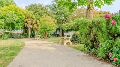 a park with two benches and flowers and trees at Appartement Cosy - Résidence avec Parc et Piscine in Marans