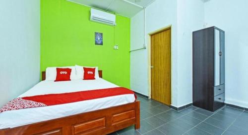 a green bedroom with a bed with red pillows at OYO 90315 Chalet Pantai Rantau Panjang in Kuala Rompin