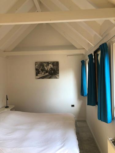 a bedroom with a white bed and blue curtains at Globetrotter in Bergen