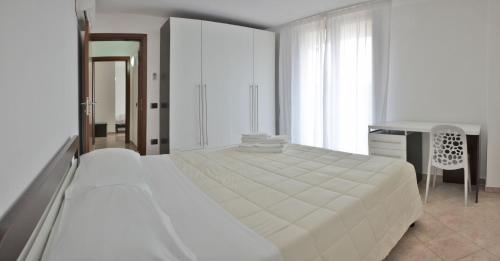 a white bedroom with a bed and a desk at Vea Resort Hotel in Mercato San Severino
