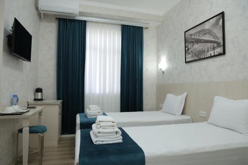 a hotel room with two beds and a window at HOTEL MERCURI-MERIDIAN in Bukhara