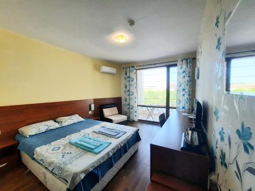 a bedroom with a bed and a large window at Family hotel Delfa in Chernomorets