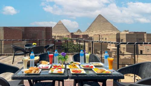 a table with plates of food on a balcony with pyramids at Turquoise Pyramids Gate Hotel City Centre in Cairo