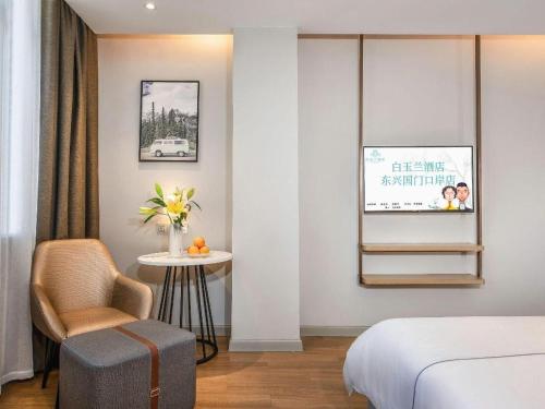 a bedroom with a bed and a chair and a table at Magnotel Hotel Dongxing Guomen Port in Fangcheng