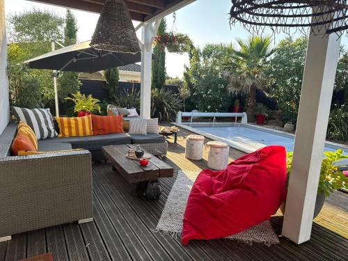 - une terrasse avec des canapés et un parasol à côté de la piscine dans l'établissement Villa carioca, à Gujan-Mestras