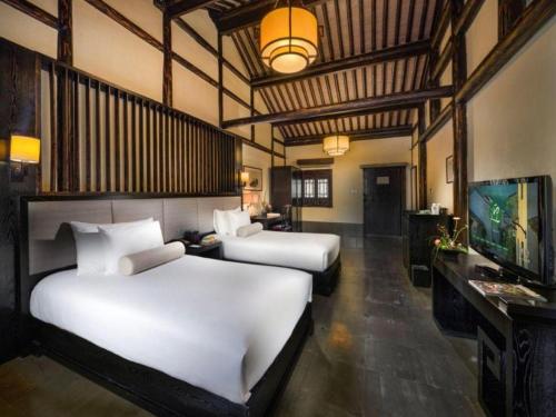 a hotel room with two beds and a television at Hotel Dayu Kaiyuan in Shaoxing