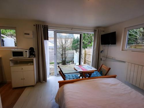 - une chambre avec un lit et une table avec un four micro-ondes dans l'établissement La petite cabane, à Honfleur