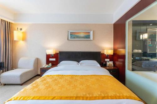 a hotel room with a large bed and a chair at Shantou Golden Gulf Hotel in Shantou