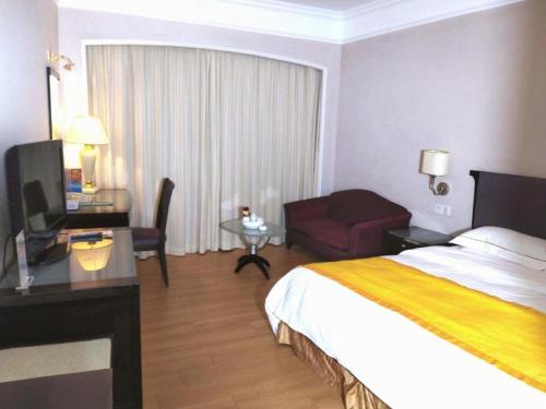 a hotel room with a bedroom with a bed and a desk at Shantou Golden Gulf Hotel in Shantou