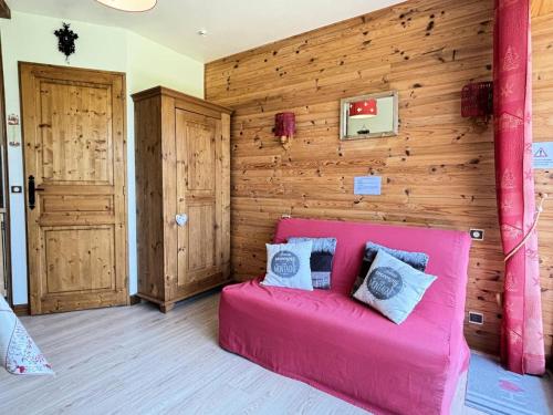 - un canapé rose dans une chambre avec un mur en bois dans l'établissement Résidence Les Alpages - Studio skis aux pieds en rez-de-jardin MAE-3833, à Notre-Dame-de-Bellecombe