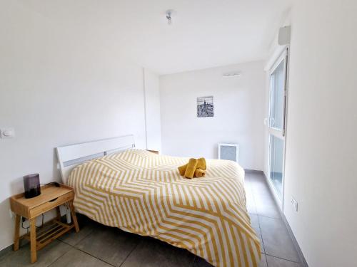 une chambre avec un lit avec une couverture jaune et blanche dans l'établissement Toit-terrasse avec vue magnifique sur Montpellier, à Montpellier