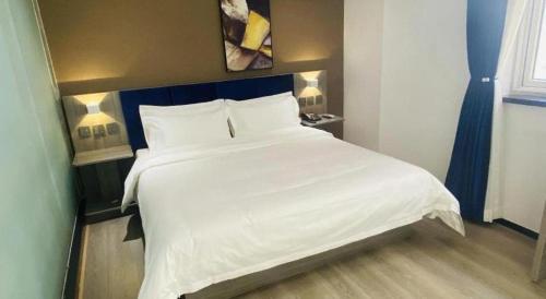 a large white bed in a room with two lamps at 7 Days Inn Baoding Railway Station in Baoding