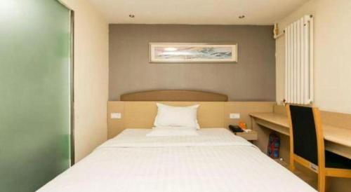 a bedroom with a large white bed and a desk at 7 Days Inn Changchun Zhengyang Street Changchun Park Branch in Changchun