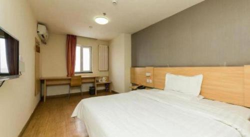 a bedroom with a large white bed and a desk at 7 Days Inn Changchun Zhengyang Street Changchun Park Branch in Changchun