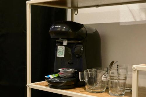 a coffee maker sitting on top of a shelf with glasses at Capstay - Roubaix - Grande Rue l Netflix - Wifi in Roubaix