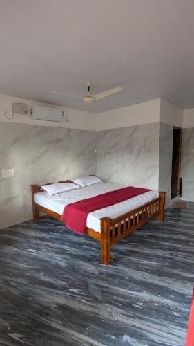 a bedroom with a large bed with a red blanket at Shri Eshwari Homestay Murdeshwar in Māvalli