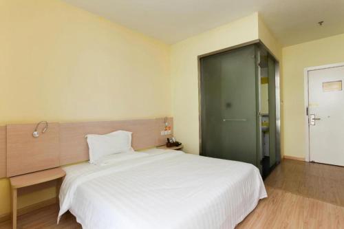 a bedroom with a large white bed and a green door at 7 Days Inn Suzhou Wangting Pearl Commercial Plaza in Suzhou