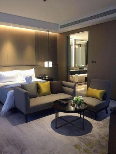 a hotel room with a bed and a couch and a table at Golden Eagle Summit Hotel Kunshan in Suzhou