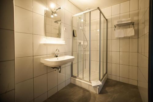 La salle de bains est pourvue d'une douche en verre et d'un lavabo. dans l'établissement Hotel Taurus, à Cuijk
