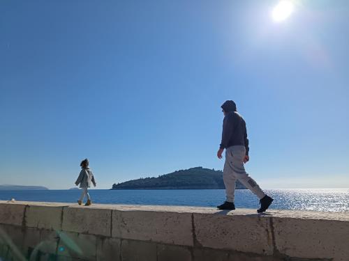 a man and a woman walking along a wall by the water at Apartment by CITY WALLS perfect for 2 in Dubrovnik