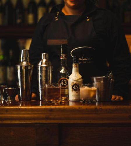 a woman standing behind a counter with cocktails and alcohol at Suites H la ermita in San Miguel de Allende