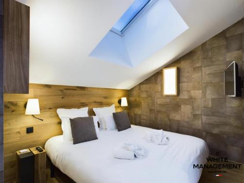 - une chambre avec un grand lit blanc et une lucarne dans l'établissement Résidence Ariondaz Anemone - Penthouse familial skis aux pieds MAE-4724, à Courchevel