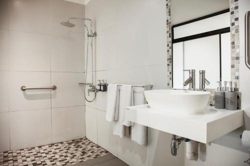 a white bathroom with a sink and a shower at Yalla Yalla Boutique Hotel in Witbank