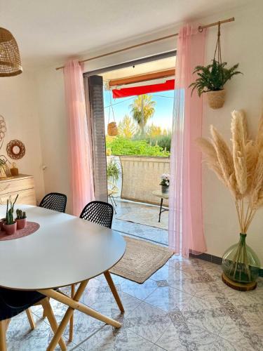 une salle à manger avec une table et des chaises blanches et un patio dans l'établissement L'appart de Coco - Idéal pour découvrir Cassis, à Cassis