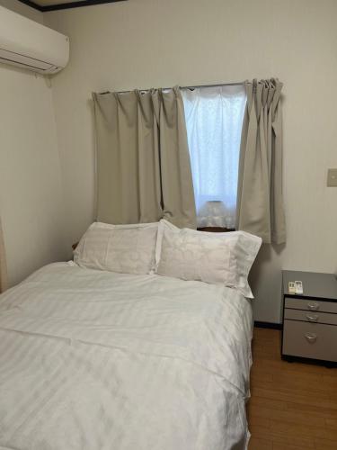 a bedroom with a white bed with a window at 西池袋之家 in Tokyo