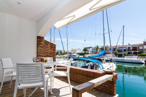 a patio with a table and chairs and a boat at Vista Roses Mar - Casa Pescador in Empuriabrava