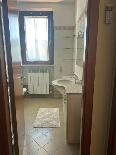 a white bathroom with a sink and a window at Casa vacanze Levata del sole in Porto Potenza Picena