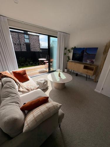 a living room with a white couch and a large window at Luxury And Serene 2 Bed Near CBD With Parking in Christchurch