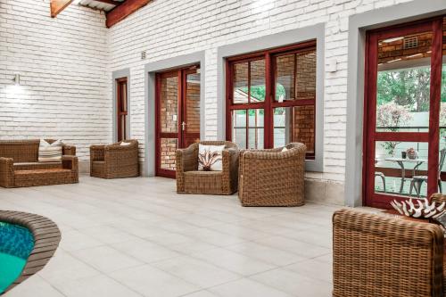a patio with wicker chairs and tables and windows at Yalla Yalla Boutique Hotel in Witbank