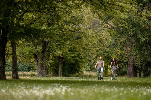 a man and woman riding bikes in a park at Hotel Apollo Terme in Montegrotto Terme