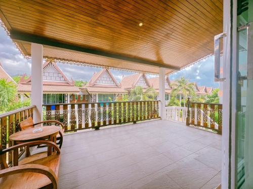 a covered porch with a table and chairs at Aura Samui Best Beach Hotel - SHA Plus in Lamai