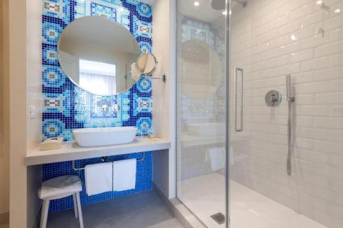 a blue tiled bathroom with a sink and a shower at Hotel Apollo Terme in Montegrotto Terme