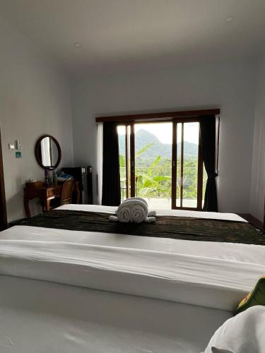 a bedroom with a large bed with a large window at Sidemen padi villas in Silebeng