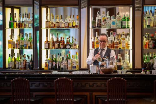 a man standing at a bar making a drink at Hotel Apollo Terme in Montegrotto Terme