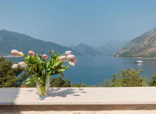 a vase of flowers sitting on a table with a lake at Villa Milica in Ljuta