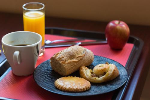 a plate of bread and an apple and a cup of coffee at Brit Hotel Terminus in Angoulême