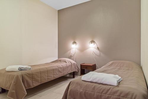 two beds in a room with two lamps on the wall at Yllästar 3, 1 bedroom & sauna in Äkäslompolo