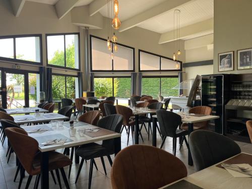 une salle à manger avec tables, chaises et fenêtres dans l'établissement Cit'Hotel Les Eleis, à Saint-Martin-de-Fraigneau