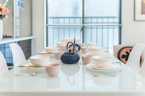 a white table with cups and saucers on it at QiQi House Tokyo まるごと新築一軒家宿 Spacious New Home, 8 Guests, Easy Airport & Disney Access in Tokyo
