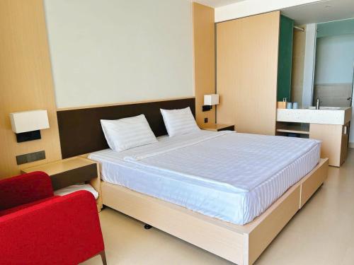a bedroom with a large bed and a red chair at Arena jakovi condotel in Cam Ranh