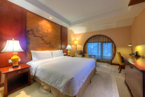 a hotel room with a large bed and a desk at Wyndham Garden Suzhou in Suzhou