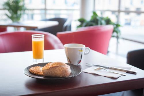 a table with a plate of food and a cup of orange juice at Brit Hotel Terminus in Angoulême